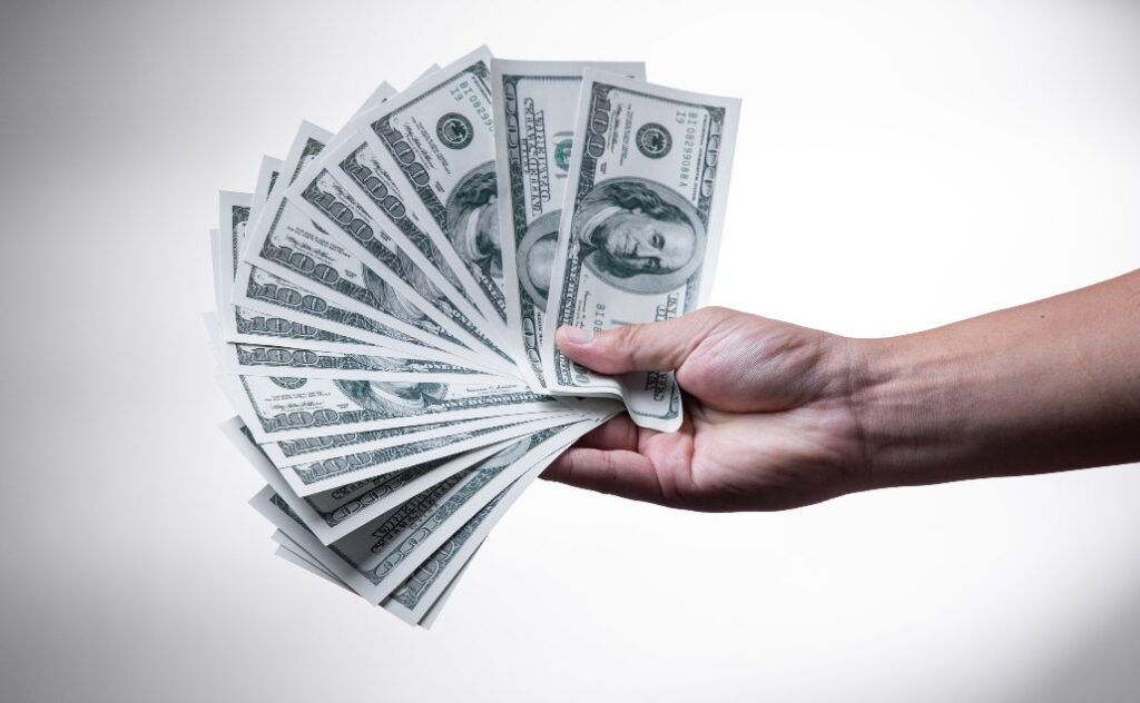 a hand holding $100 bills