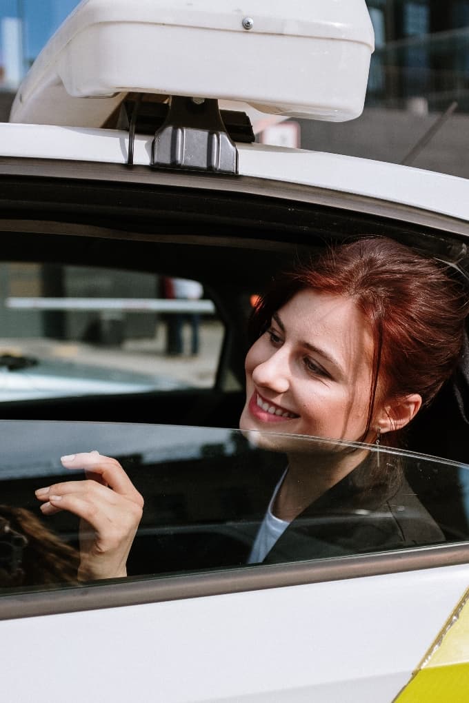 a woman riding in a taxi, smiling
