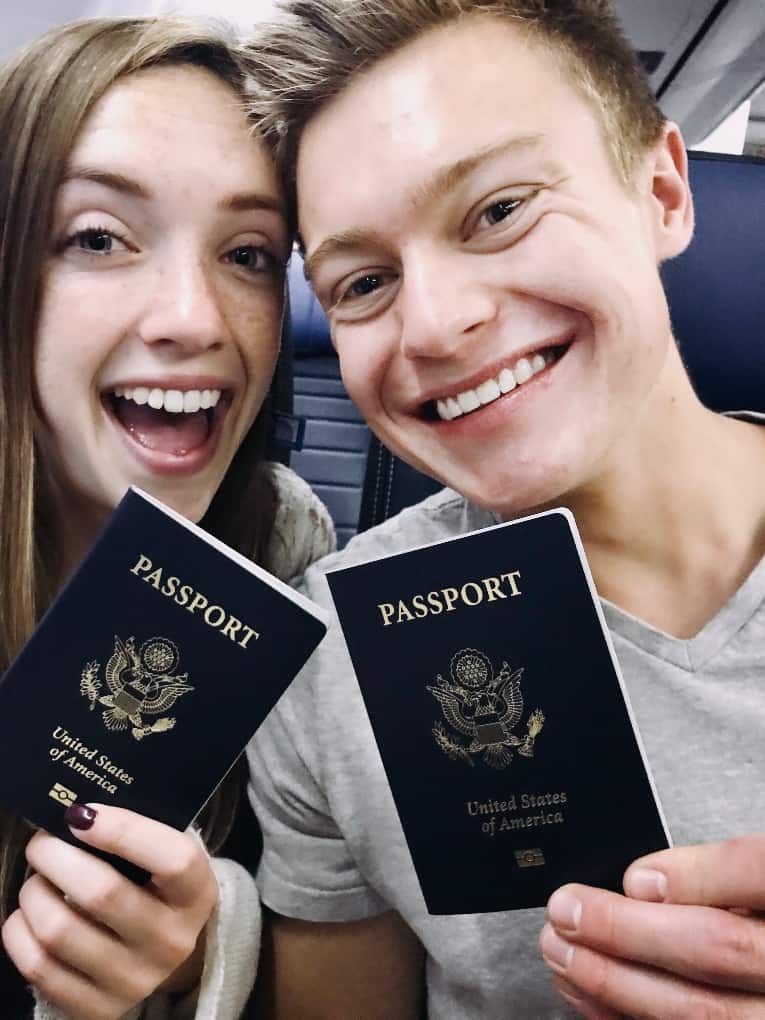 Janelle and Peter holding passports on an airplane