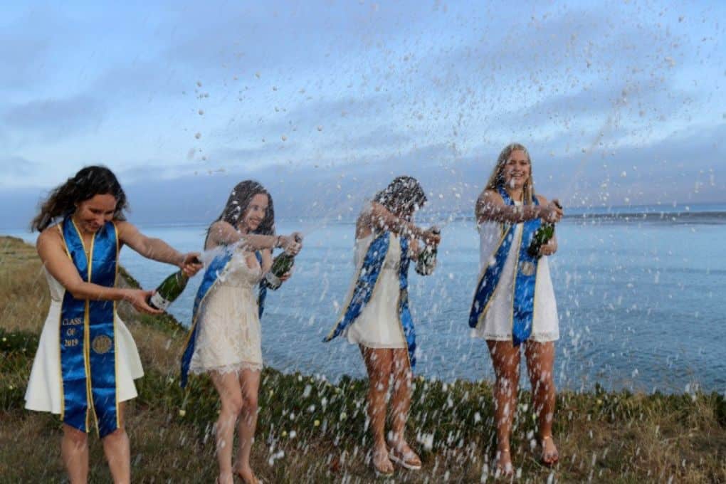 girls popping champagne during college graduation
