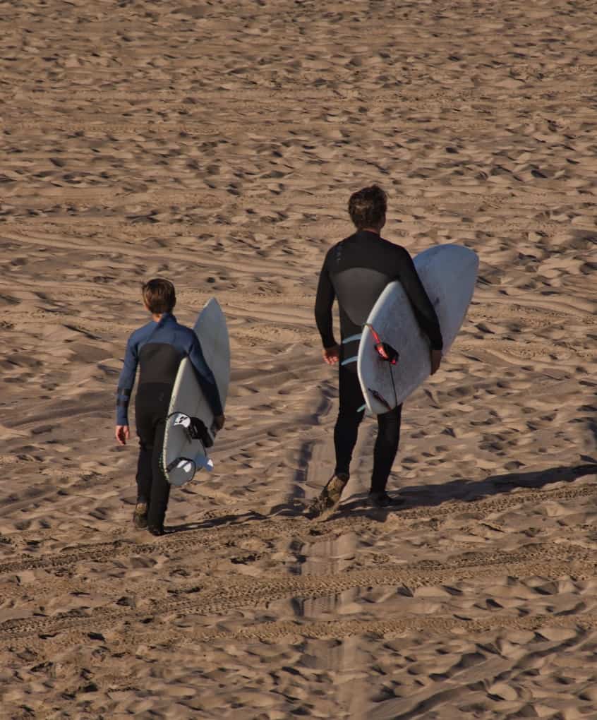 two surfers wearing wetsuits