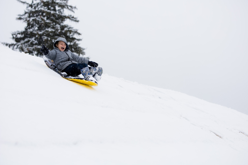 a kid sledding down a snow hill