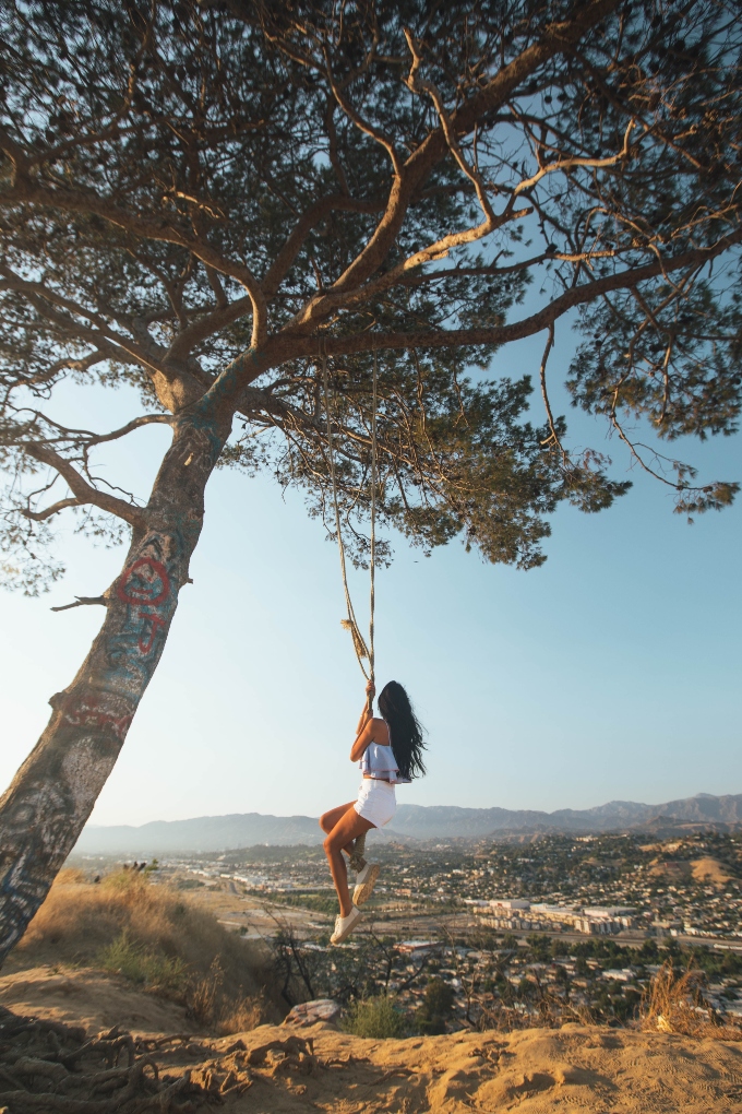 girl swinging from a tree overlooking Los Angeles