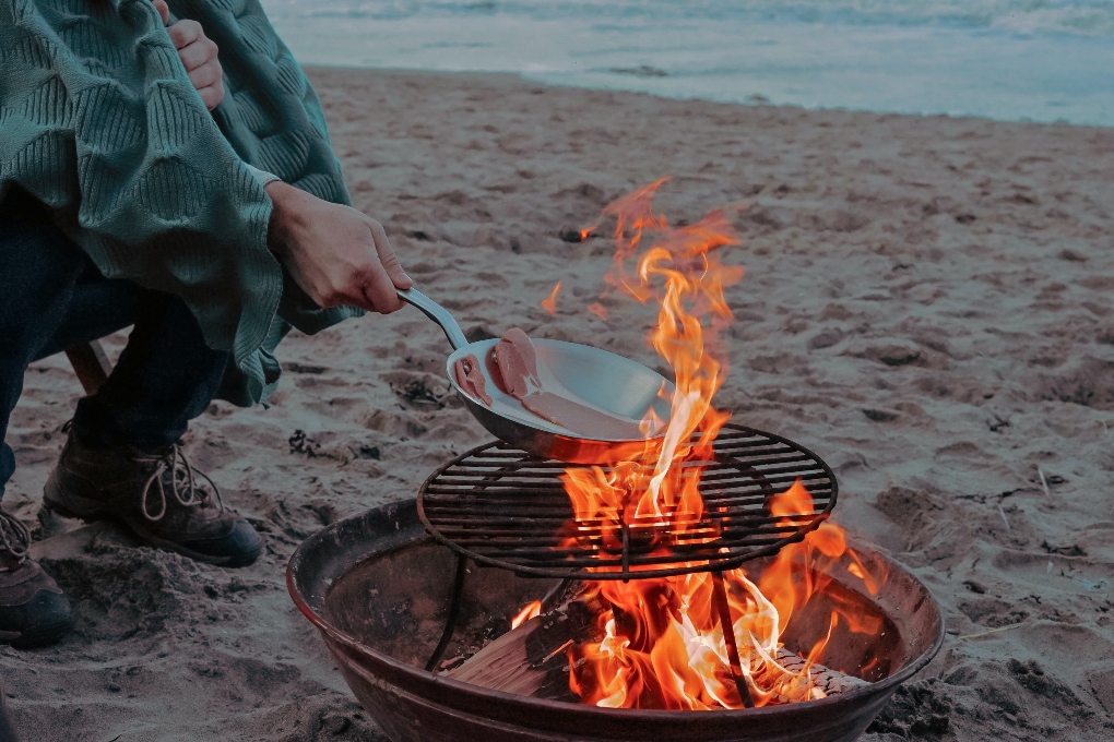 grilling meat on a beach fire